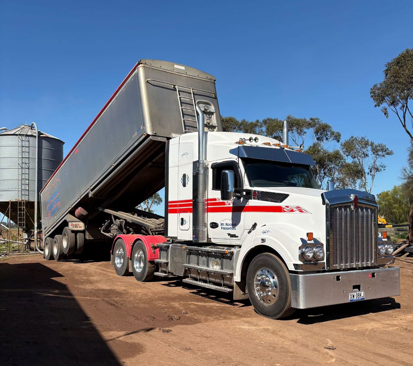 Mt Noorat Freighters prime mover with one bulk trailer raised beside a farm silo at Glenfyne, Victoria.